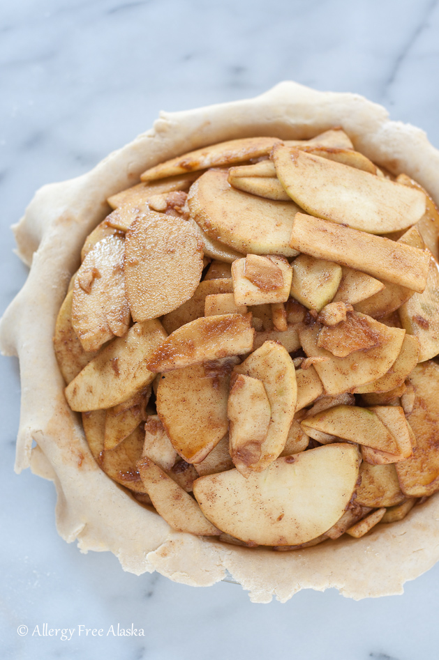 raw gluten free apple pie waiting for top crust sitting on marble background