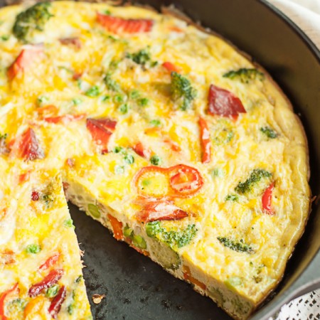 side angle of cast iron pan filled with smoked salmon frittata with slice missing