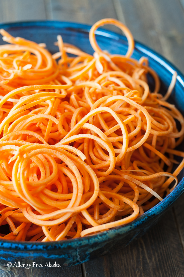 a blue bowl filled with spiralized sweet potato noodles