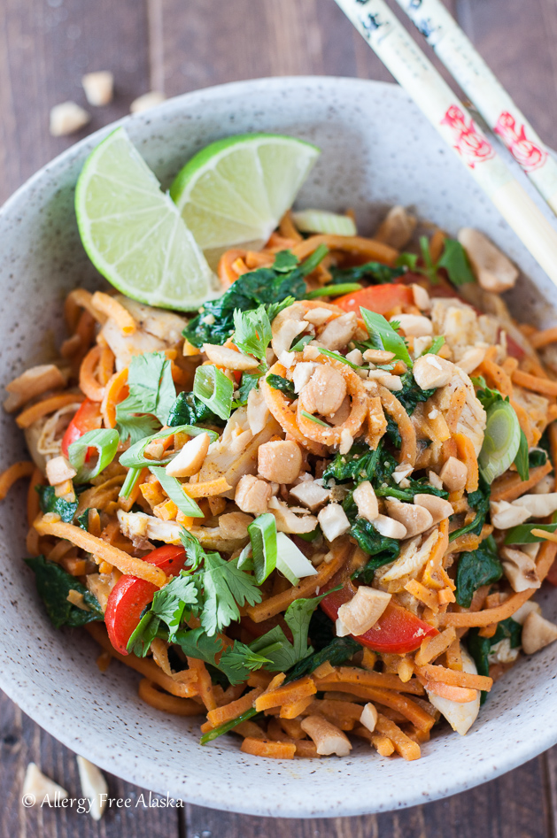 thai chicken & sweet potato stir fry in a white bowl with lime wedges