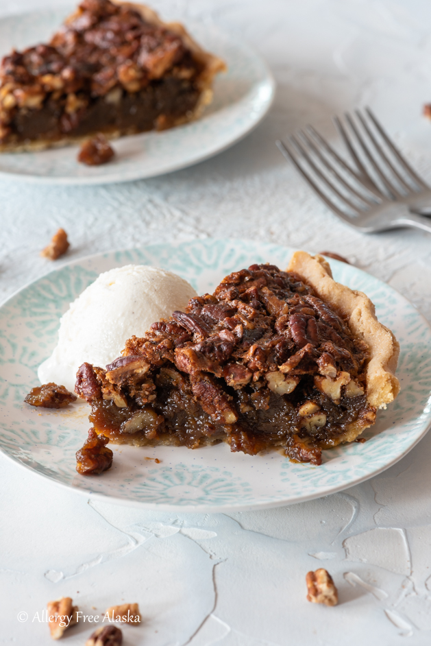 slice of gluten free pecan pie sitting on plate with scoop of ice cream