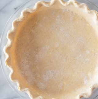 prepared raw gluten-free pie crust sitting on top of marble pastry board waiting to be filled