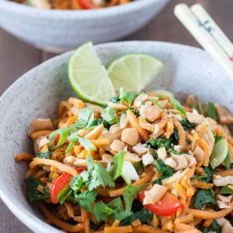 thai chicken sweet potato noodle bowl with lime wedges and chop sticks