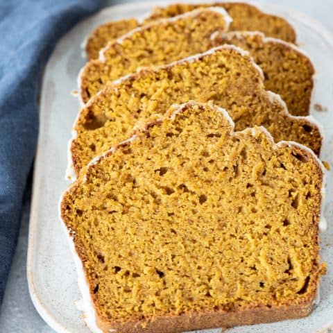 4 pieces of sliced gluten-free pumpkin bread sitting on white platter shot from different angle