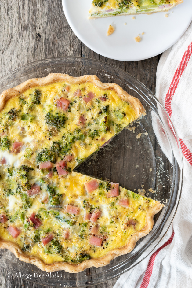 overhead shot of dairy-free quiche in clear pie plate with a slice missing