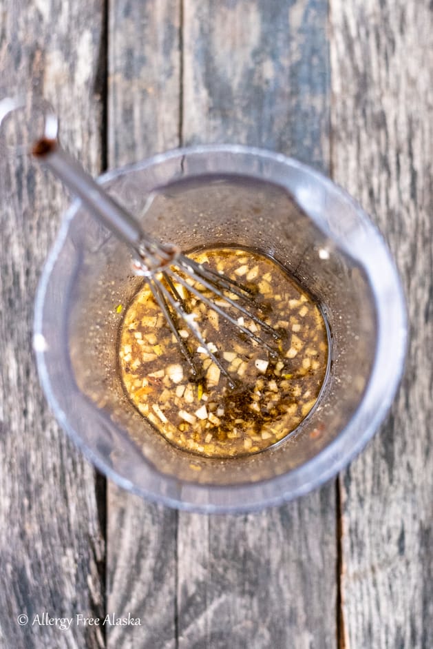 top down view of beef ribs marinade in plastic container with whisk