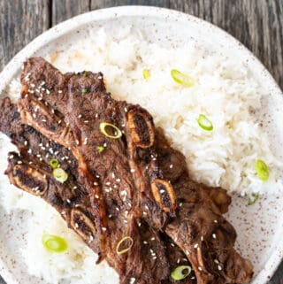 Top down view flanken ribs on pile of rice sitting on speckled brown and white plate