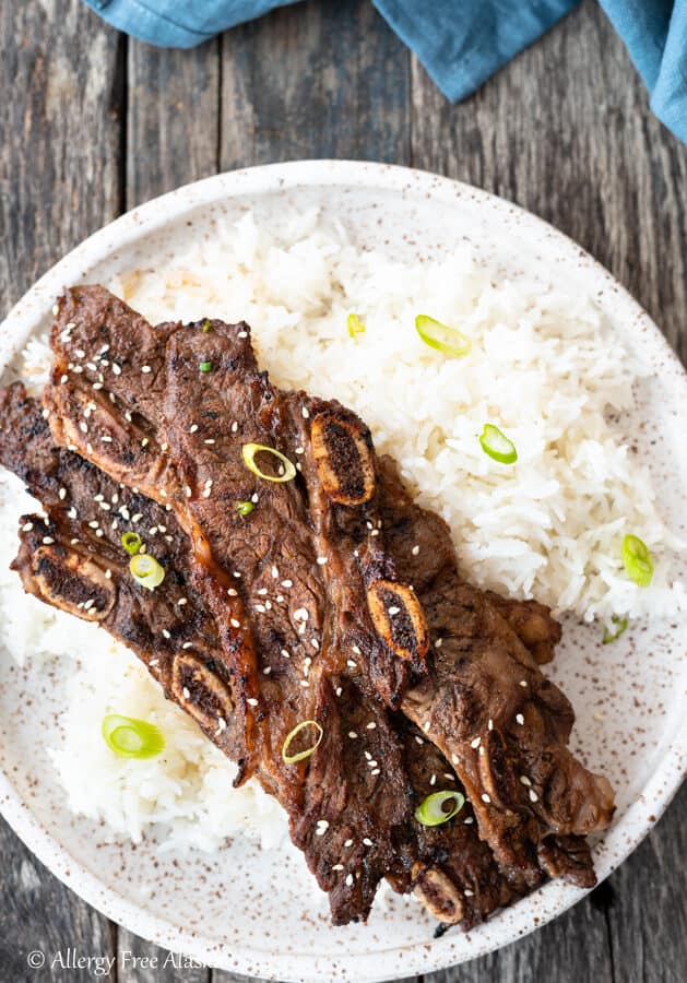 Top down view flanken ribs on pile of rice sitting on speckled brown and white plate