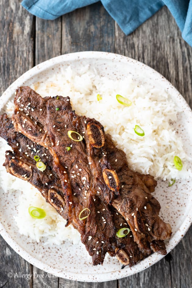 Top down view flanken ribs on pile of rice sitting on speckled brown and white plate