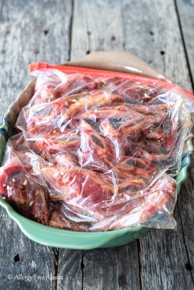 flanken style ribs in bag with marinade sitting in green baking dish
