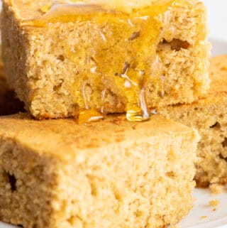 gluten-free cornbread stacked on plate with honey dripping down the side