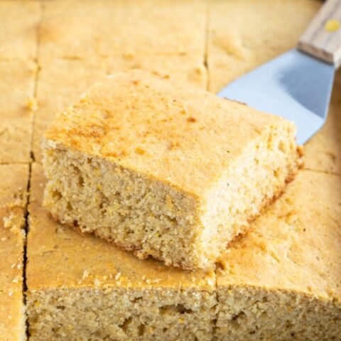 pan of sliced gluten-free cornbread with spatula holding 1 piece