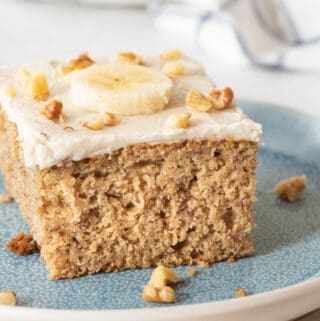 slice of gluten free cake topped with a banana slice and chopped walnuts