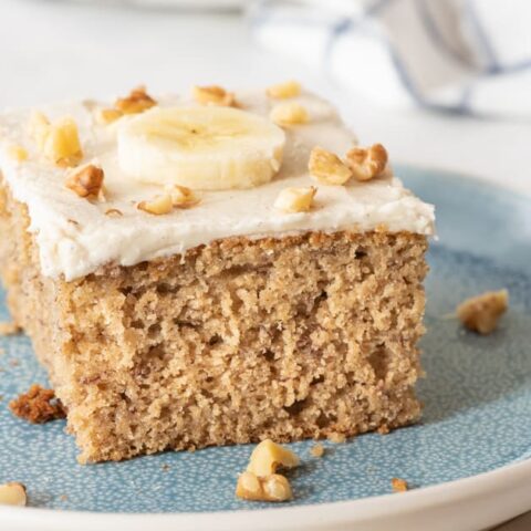 slice of gluten free cake topped with a banana slice and chopped walnuts