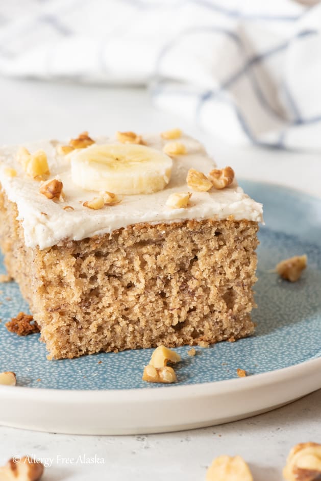 slice of gluten free cake topped with a banana slice and chopped walnuts
