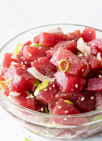 side view of poke salad in clear bowl on white background