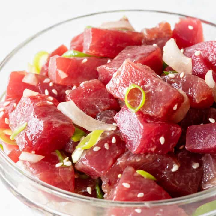 side view of poke salad in clear bowl on white background