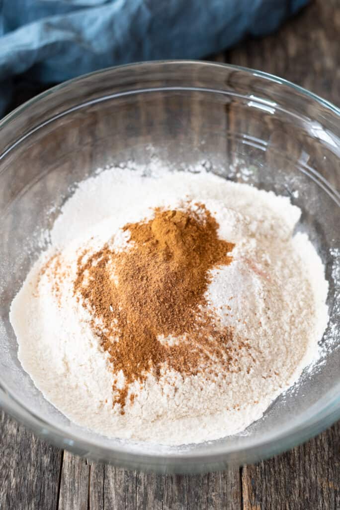 dry flour and spices in large clear mixing bowl on wooden background