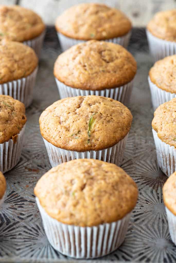 gluten free zucchini muffins in white paper liners sitting on metal tray