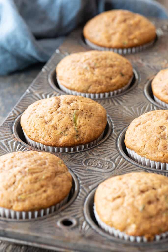 gluten free zucchini muffins in white paper liners sitting in vintage muffin tin