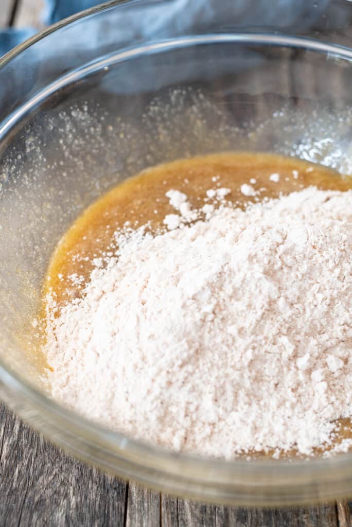 dry gluten free flour sitting on top of wet ingredients in large clear bowl