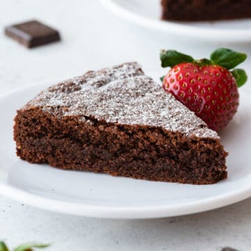 close up view of almond flour chocolate cake slice on white plate with strawberry