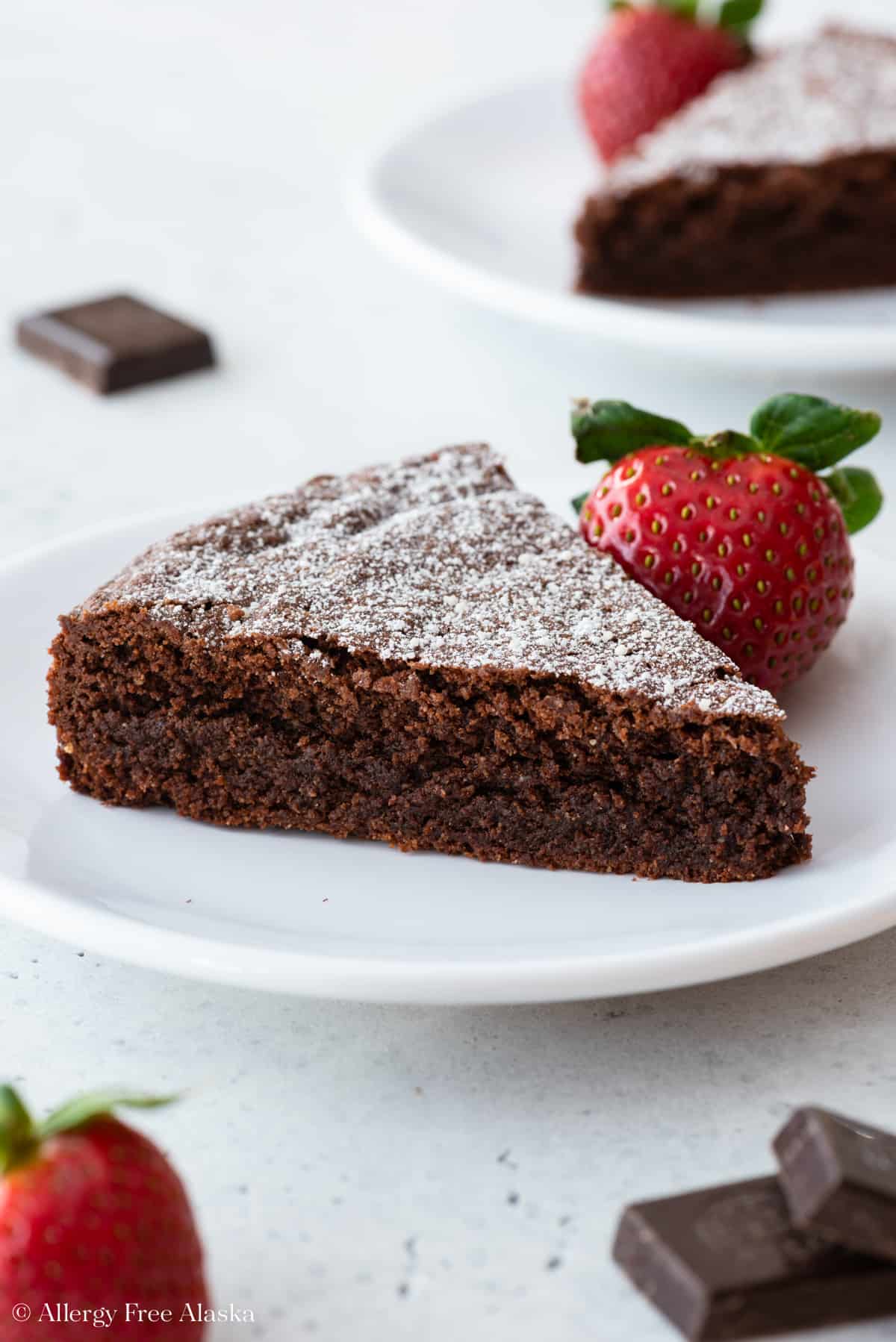 close up view of almond flour chocolate cake slice on white plate with strawberry