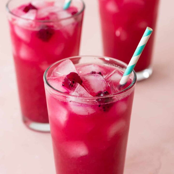 3 mango dragon fruit lemonades in clear glasses with ice and blue/white straws - at different angle