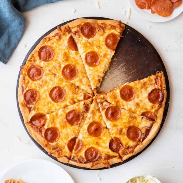 Top down view pepperoni pizza gluten free with missing slice to side on white plate