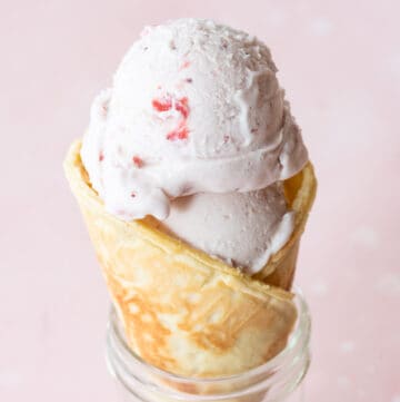 single ice cream cone in clear mason jar on pink background