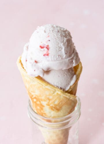 single ice cream cone in clear mason jar on pink background
