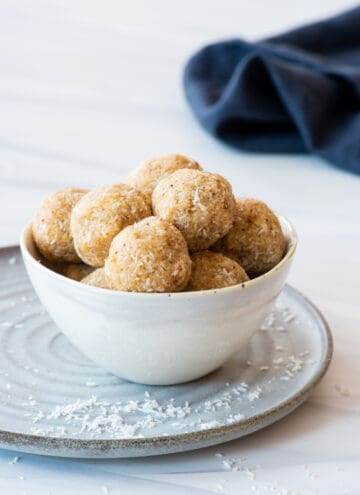 At different angle: Bowl of caramel coconut cookies sitting on gray plate with blue napkin in background