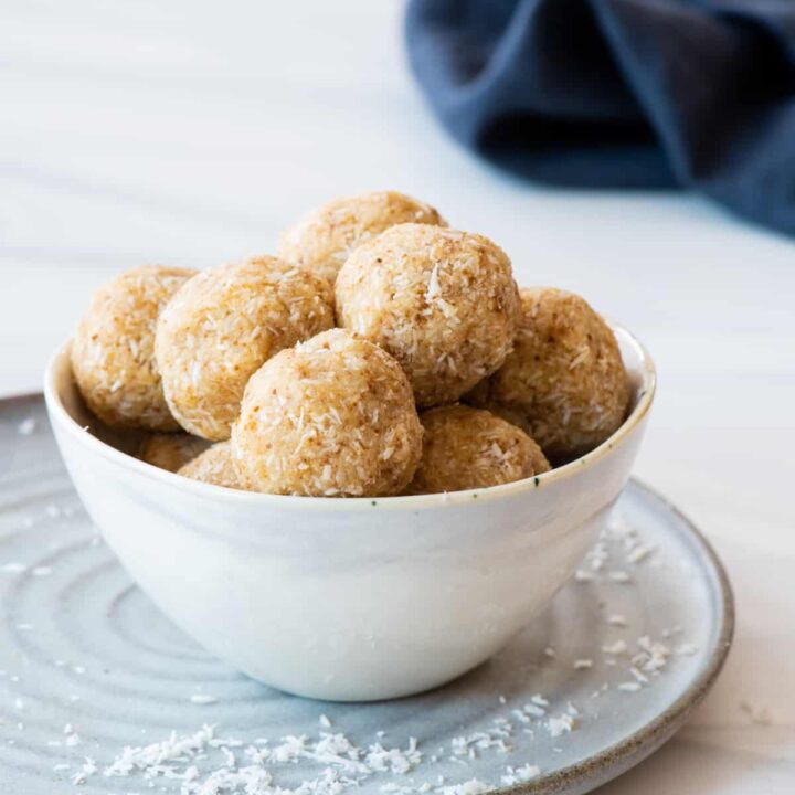At different angle: Bowl of caramel coconut cookies sitting on gray plate with blue napkin in background